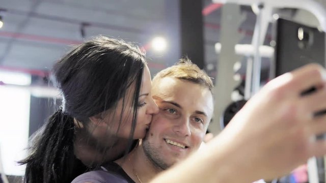 Young attractive man and woman are doing selfie in the gym