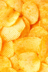 Background of golden wavy corrugated chips large slices with seasoning throughout the frame, appetizing food background