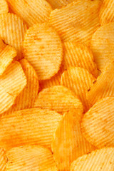 Background of golden wavy corrugated chips large slices with seasoning throughout the frame, appetizing food background