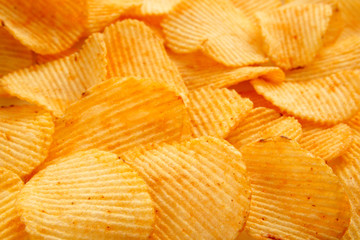 Background of golden wavy corrugated chips large slices with seasoning throughout the frame, appetizing food background