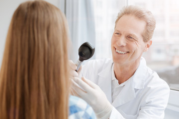 Delighted mature doctor using special equipment in the clinic