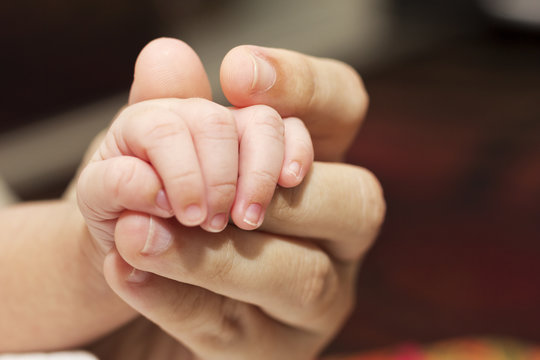 A newborn holding his mothers finger. A concept of love and security.