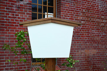 Empty billboard in front of red brick wall