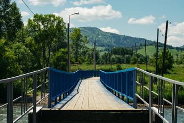 Human interaction with wildlife. A bridge across a mountain river among the hills. Electric posts. Street lighting.