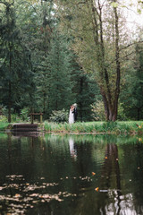 Wedding couple walks along lake's shore in the park