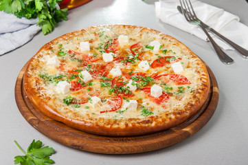 Four cheese pizza quattro fromaggi on a rustic wooden board on the table with ingridients. Selective fovus