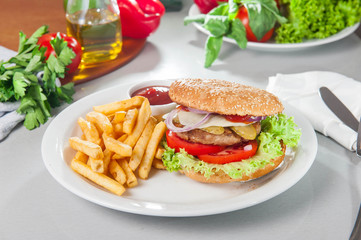 Tasty burger set - meat burger, french fries and sause on the white round plate on the served table with fresh ingridients. Close- up. selective focus. Unhealthy food concept