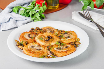 Potato pancakes with mushrooms on the white plate on the table with different bright ingredients, restaurant menu, Selective focus