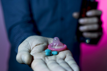 man with mixed drink, blue pills and condom
