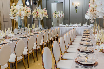 Bouquets of white orchids and pink roses put in vases stand on long dinner tables