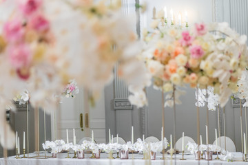 Look between vases at long dinner table served for newlyweds
