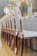 Chairs with round backs stand side by side at long dinner table