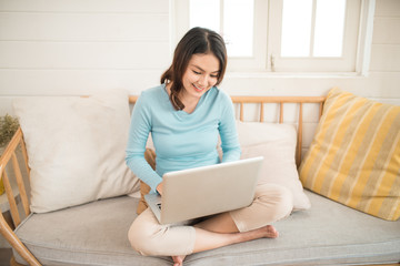 Naklejka premium Happy casual beautiful asian young woman working on a laptop at home.