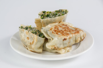 pan-fried leek dumplings on a plate isolated on white background
