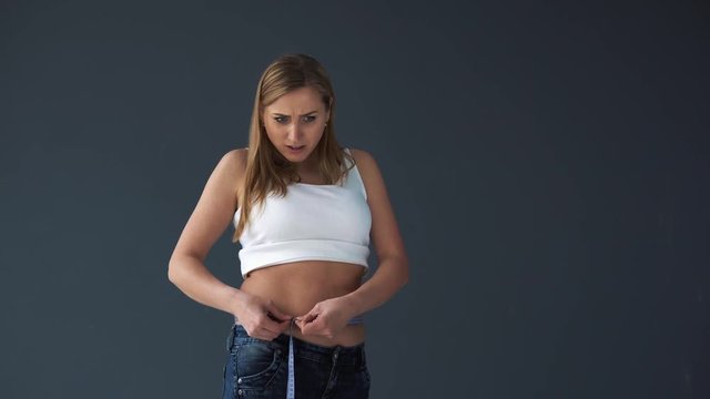 Overweight Female woman measuring her waist with a measuring tape. She was disappointed at her complete figure