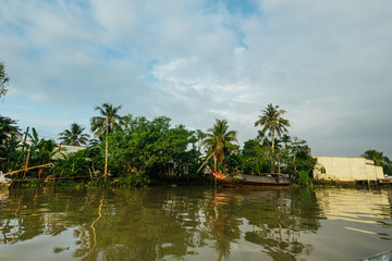 Boat floats alongt he shore with palms in Vietnam