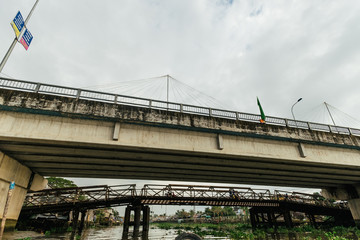 Look from below at old grey bridge under white sky