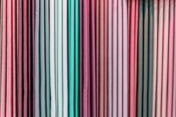 Obraz premium Colorful curtain samples hanging from hangers on a rail in a display in a retail store