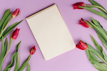 Notebook mock up for artwork with red tulips on violet background. View from above.