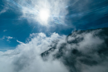 Obraz na płótnie Canvas Bright sun shines over the mountain covered with fog