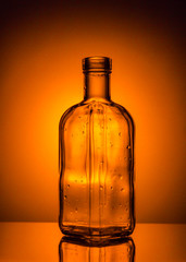 Bottle with drops on orange background