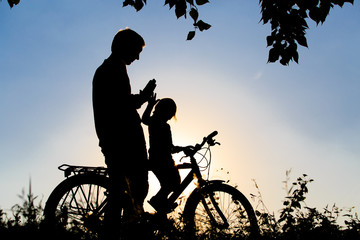 Obraz premium father and daughter riding bike at sunset