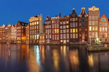 Beautiful typical Dutch dancing houses at the Amsterdam canal Damrak at night, Holland, Netherlands.
