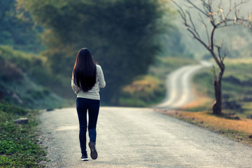 Women walk alone in the fall, the road is empty.