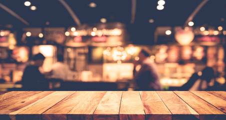 Wood table top on blurred of cafe ( restaurant ) with light gold bokeh in dark night background.For montage product display  design key visual layout.