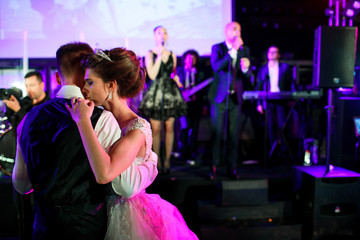 Bride leans to groom tender dancing before the stage