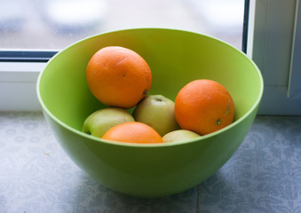 Green apples and oranges in greed bowl