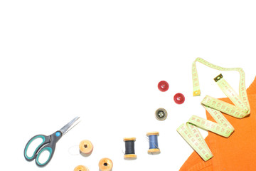 Coil with thread, scissors and ruler on a piece with a bright cloth, on a white background