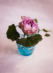 Dark green leaves and violet hydrangea put in a blue glass