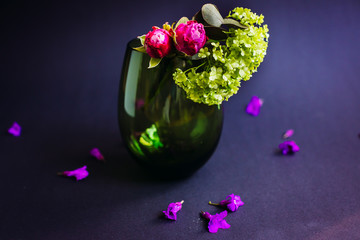 Dark glass vase with pink roses and green flowers