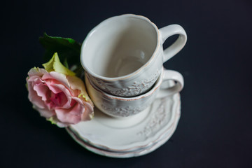 Obraz na płótnie Canvas Pink flowers lie on plate by two porcelain cups