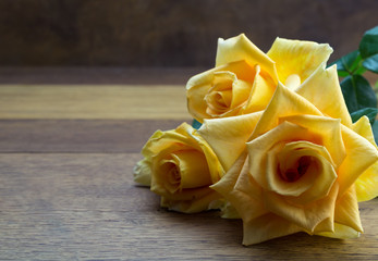 Bright large open yellow roses close up on oak wooden table - background