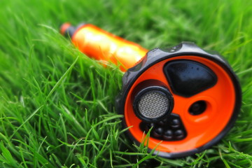 Adjustable shower (spray) lying on the fresh lawn grass in the summer garden