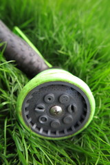 Adjustable shower (spray) lying on the fresh lawn grass in the s