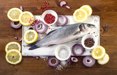 Fresh fish with  spices, salt, lemon and onion slices.  Healthy food, diet concept.