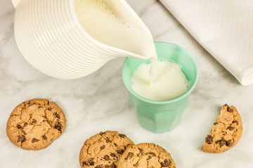 Milk poured into glass, with chocolate chips cookies
