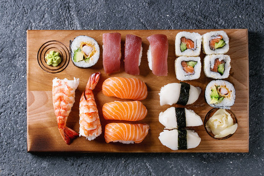 Sushi Set nigiri and sushi rolls on wooden serving board over black stone texture background. Top view with space. Japan menu