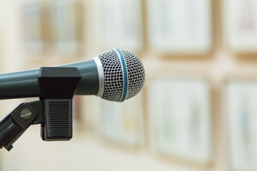 Obraz premium Dynamic microphone at the event. Exhibition hall, paintings on the walls. Focus on foreground, blurred background, bokeh.