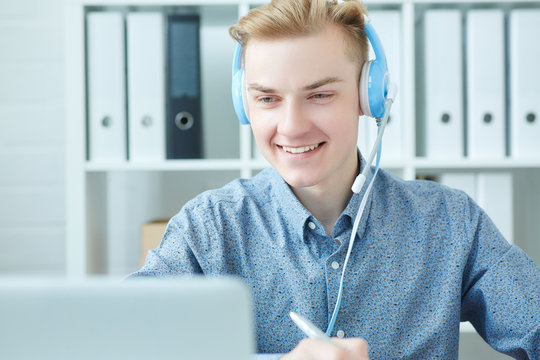 Young caucasian call center consultant with headset in office.  Effective and efficient business information, help and support concept