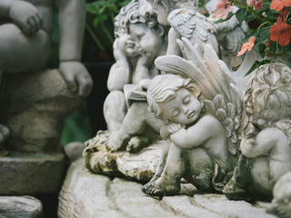 Fototapeta na wymiar A white sculpture cupid in the garden, White cute cupid statue
