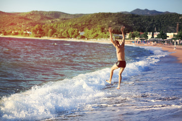 Young man jumping into the sea at sunset