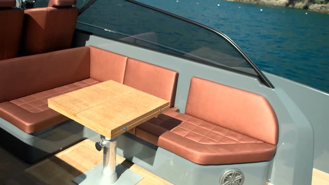 Small wooden table and sofas at the stern of a maxi rib.