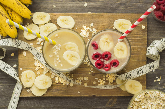 Useful and delicious smoothies. Banana with oatmeal and raspberry with banana and oatmeal on a wooden board on a black wooden background, top view