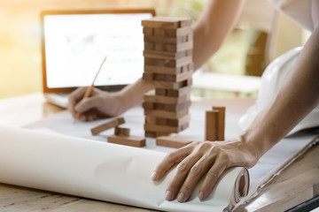 Obraz premium Projecting with pencil on the big urban drawings. Town planning and wood tower model for a architecture,architect working with vintage tone.