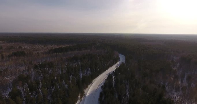 Siberia, 2017: Aerial view. The concept of the path of life, pacification, inspiration. The rural road passes between a coniferous dense forest and leaves far into the distance, beyond the horizon.