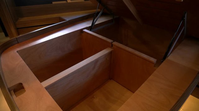 Man lifts double bed in guest cabin of a yacht to access storage spaces.